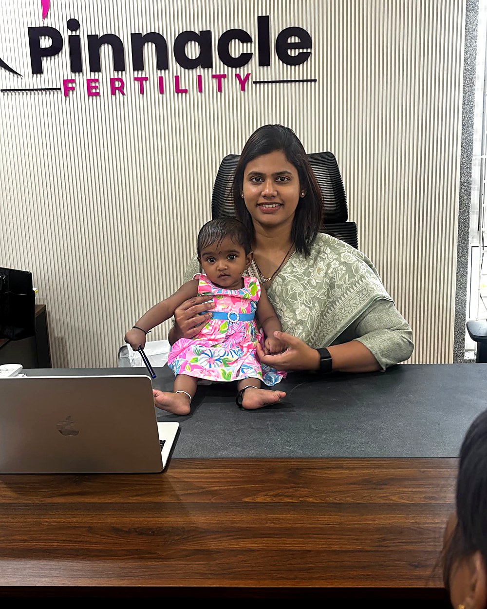 Dr. Archana with a baby girl at her Pinnacle Fertility desk