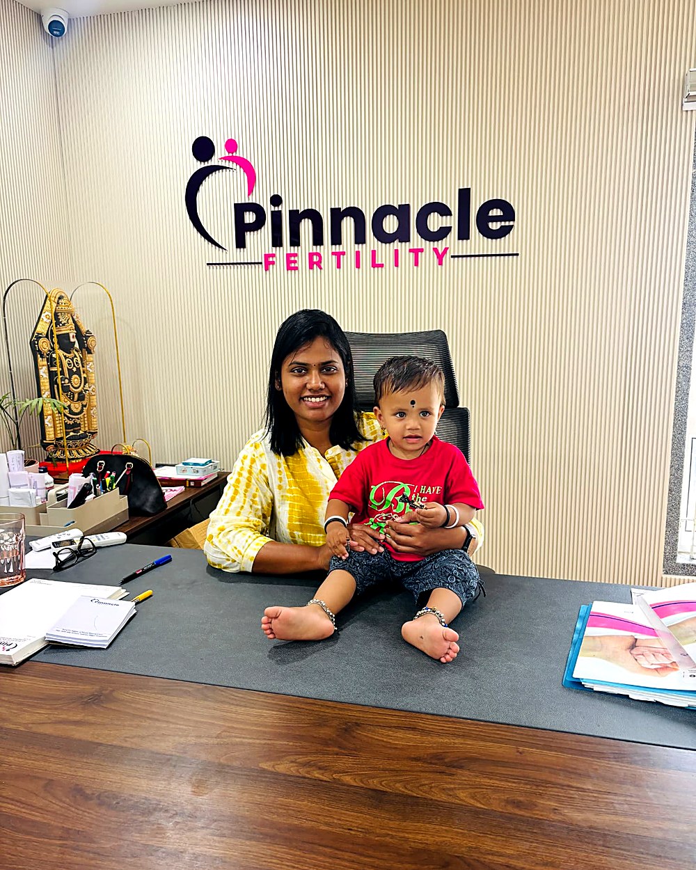 Dr. Archana with a happy toddler under the Pinnacle Fertility sign