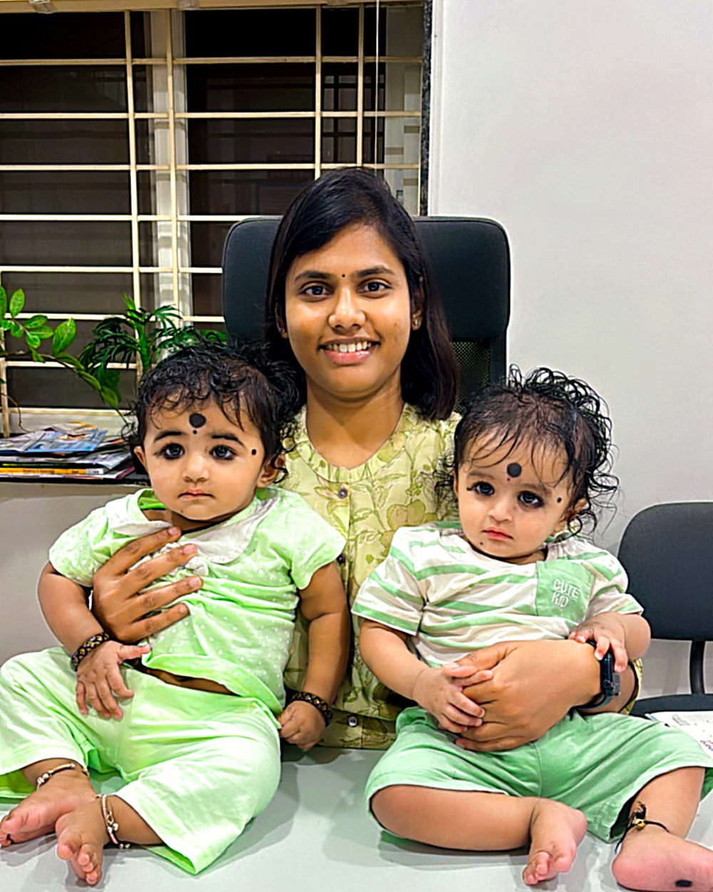 Dr. Archana with twin babies dressed in green at the clinic